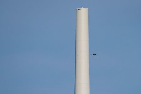 Schwarzstorch fliegt neben Windrad